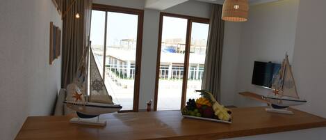 A modern room with a wooden counter, two model sailboats, a fruit bowl, and a television on the wall.