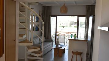 A modern interior with a spiral staircase, a sofa, a dining table, and a view through large windows.