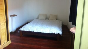 Un dormitorio con cama, mesita de noche y armario de madera.