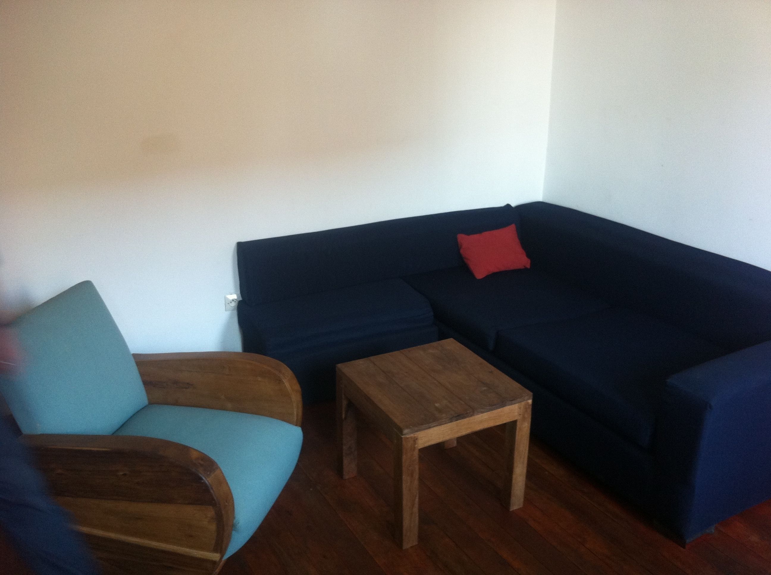 A living room with a dark blue sofa, a wooden coffee table, and a teal armchair.