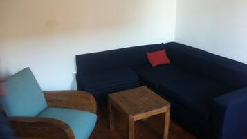 A living room with a dark blue sofa, a wooden coffee table, and a teal armchair.