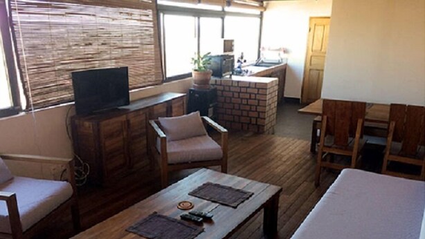 Una sala de estar acogedora con una mesa de centro de madera, sillas cómodas, un televisor y una chimenea de ladrillo.