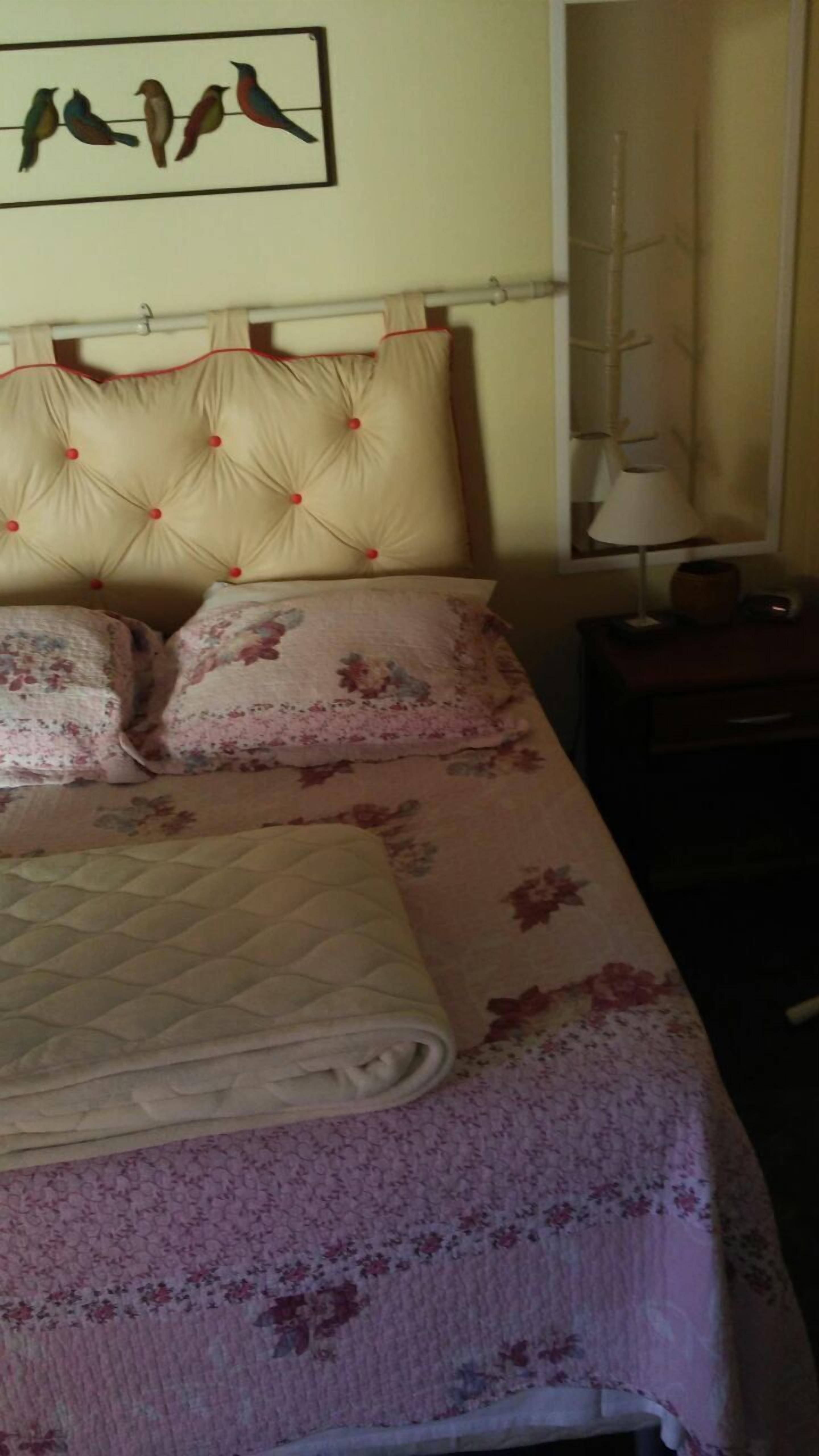 A bed with a quilted headboard, floral-patterned bedding, and a folded blanket.