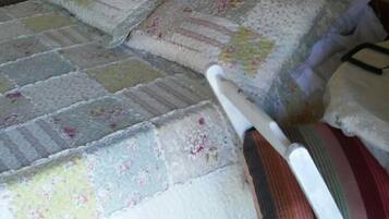 Una cama con colcha estampada, cabecera de madera y mesita de noche con lámpara.