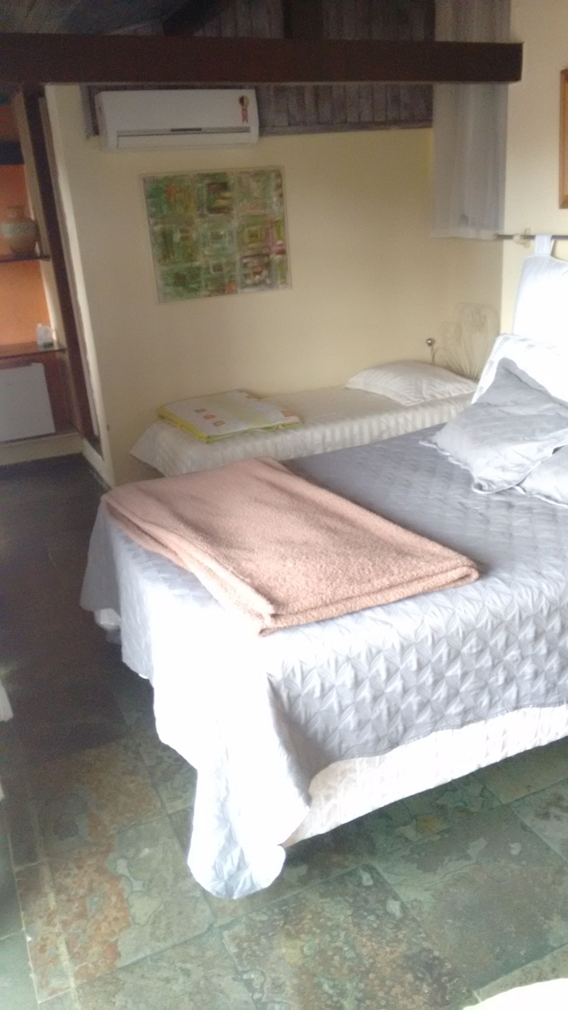 Una habitación pequeña y acogedora con una cama individual, una mesita de noche y un aire acondicionado instalado en la pared.