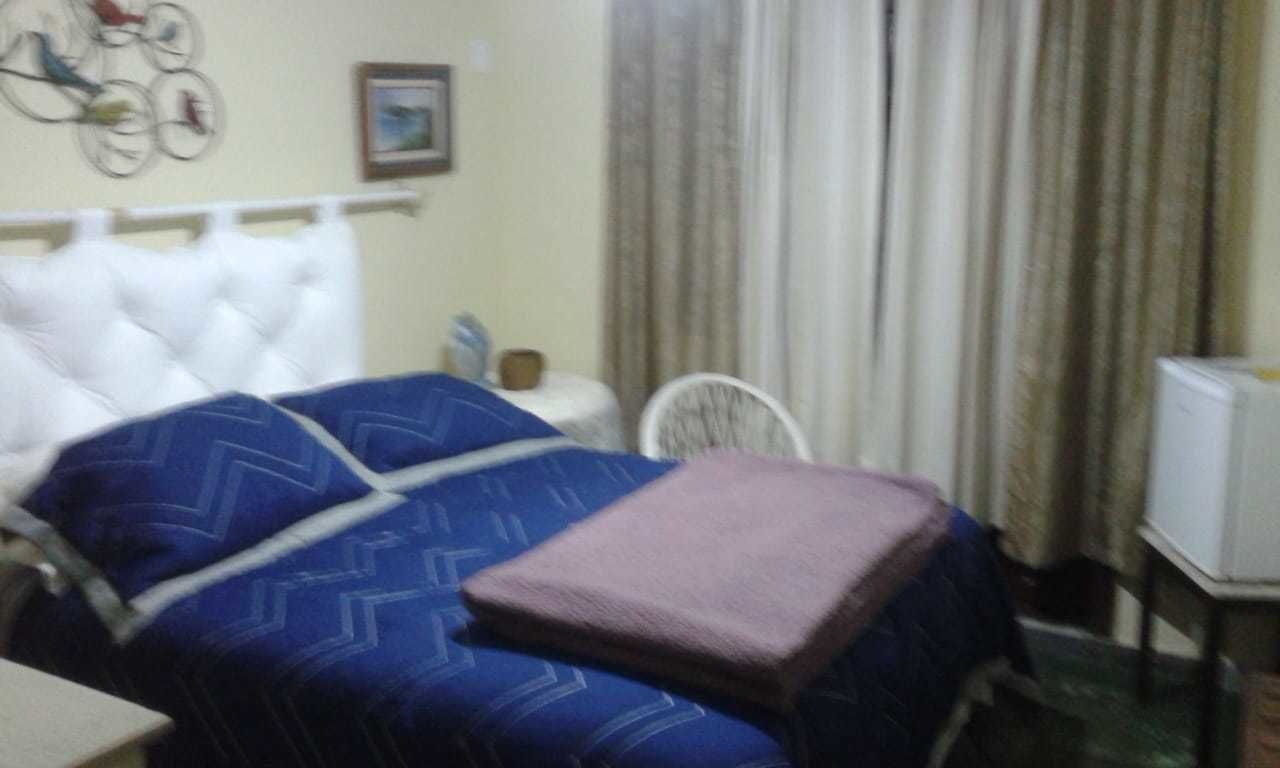 Une chambre d’hôtel avec un lit, une chaise, une petite table et un téléviseur.