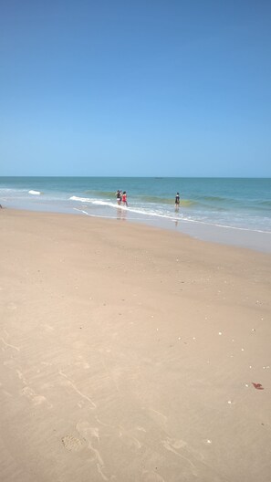A wide sandy beach with gentle waves and a clear blue sky. - Nanaay (Fatick)