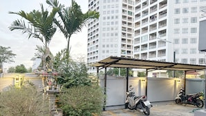 A parking area with a covered shelter, a statue, and a tall building in the background. - Goody Hotel (Bangkok)