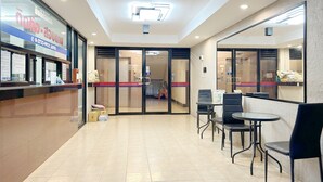 A reception area with a counter, chairs, and a tiled floor. - Goody Hotel (Bangkok)