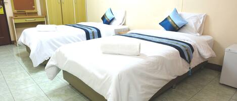 Dos camas individuales con ropa de cama blanca, franjas decorativas azules y doradas y almohadas a juego.