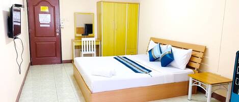 Ein Hotelzimmer mit einem Bett, einem Schreibtisch, einem Stuhl, einem Kleiderschrank und einem Fernseher.