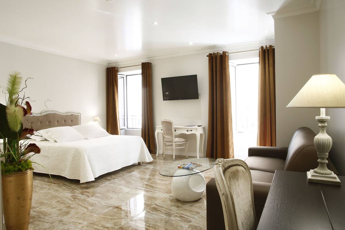 Een hotelkamer met een bed, bureau, stoel en een televisie aan de muur.