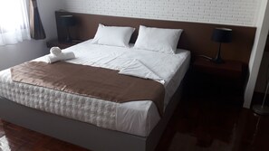 A neatly made bed with white linens and a brown throw blanket, a headboard with a white brick pattern, and two bedside lamps on wooden nightstands. - Vanilla Hostel & Bar (Pattaya)