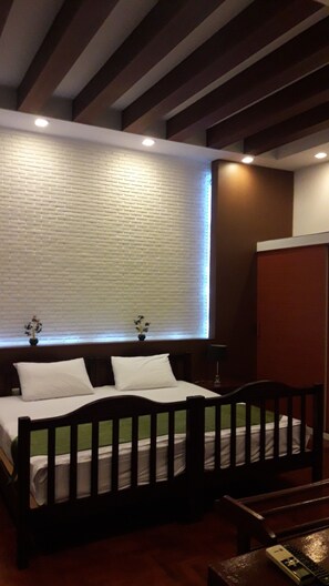 Un dormitorio con cama de madera, ropa de cama blanca, pared con diseño de ladrillo y una ventana con persianas.