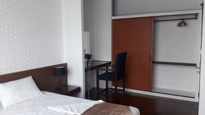 A hotel room with a bed, a desk, a chair, a lamp, and a sliding door. - Vanilla Hostel & Bar (Pattaya)