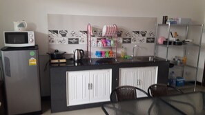 Eine kompakte Küche mit Mikrowelle, Kühlschrank, Spüle und einem kleinen Essbereich mit Stühlen.