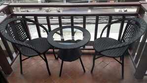 A balcony with two wicker chairs and a small round table. - Vanilla Hostel & Bar (Pattaya)