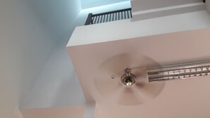 A ceiling fan with a central light fixture, a metal vent, and a white ceiling with a visible structural beam. - Vanilla Hostel & Bar (Pattaya)