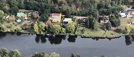 Eine Luftaufnahme einer Siedlung am Seeufer mit Häusern und dichtem Wald.