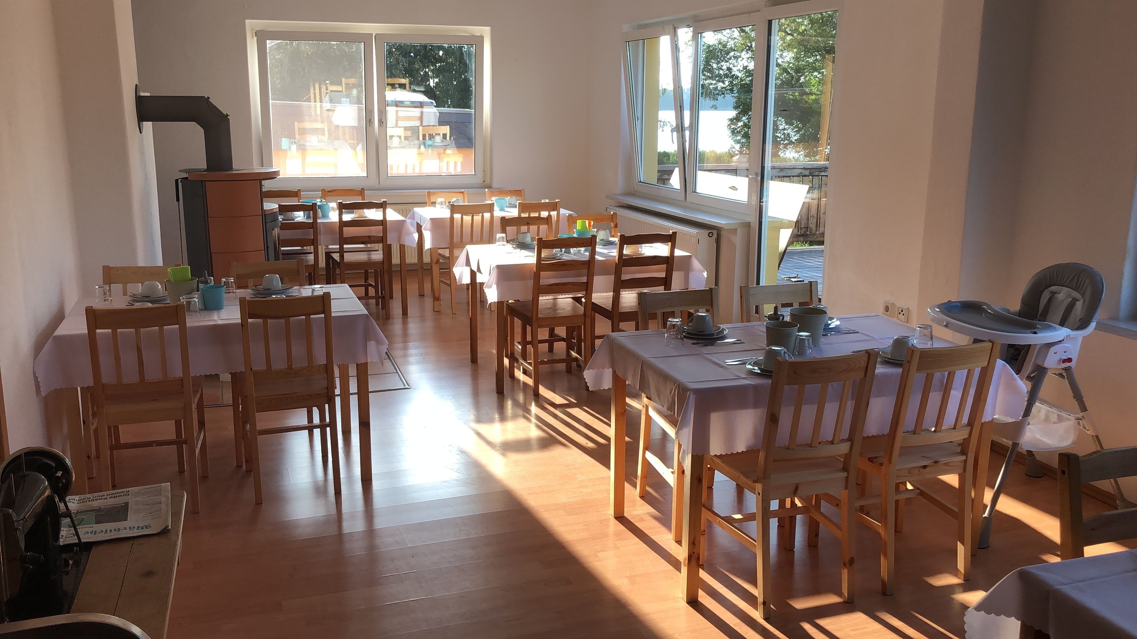 Un comedor con varias mesas y sillas, ventanas grandes y vistas al exterior.