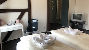 A hotel room with a bed, a desk with a computer, a TV, and a mirror.