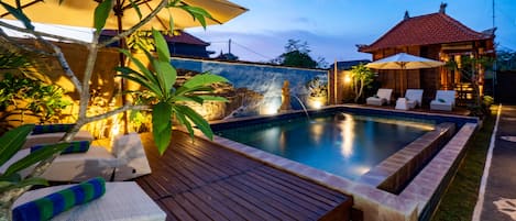 Een buitenzwembad, ligstoelen bij het zwembad