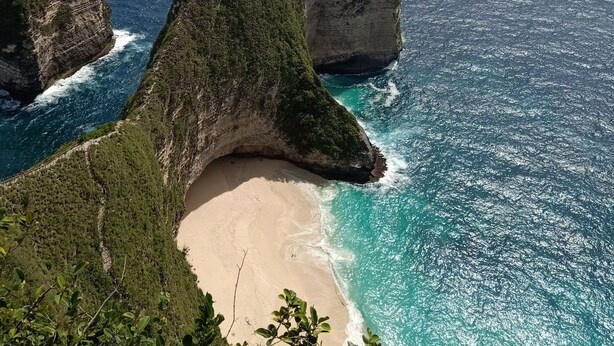 A coastal landscape with a prominent rock formation and a sandy beach.