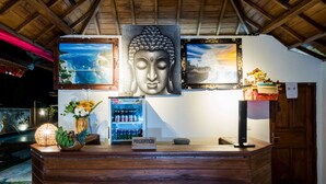 A reception desk with a Buddha painting, framed artwork, and a reception sign.