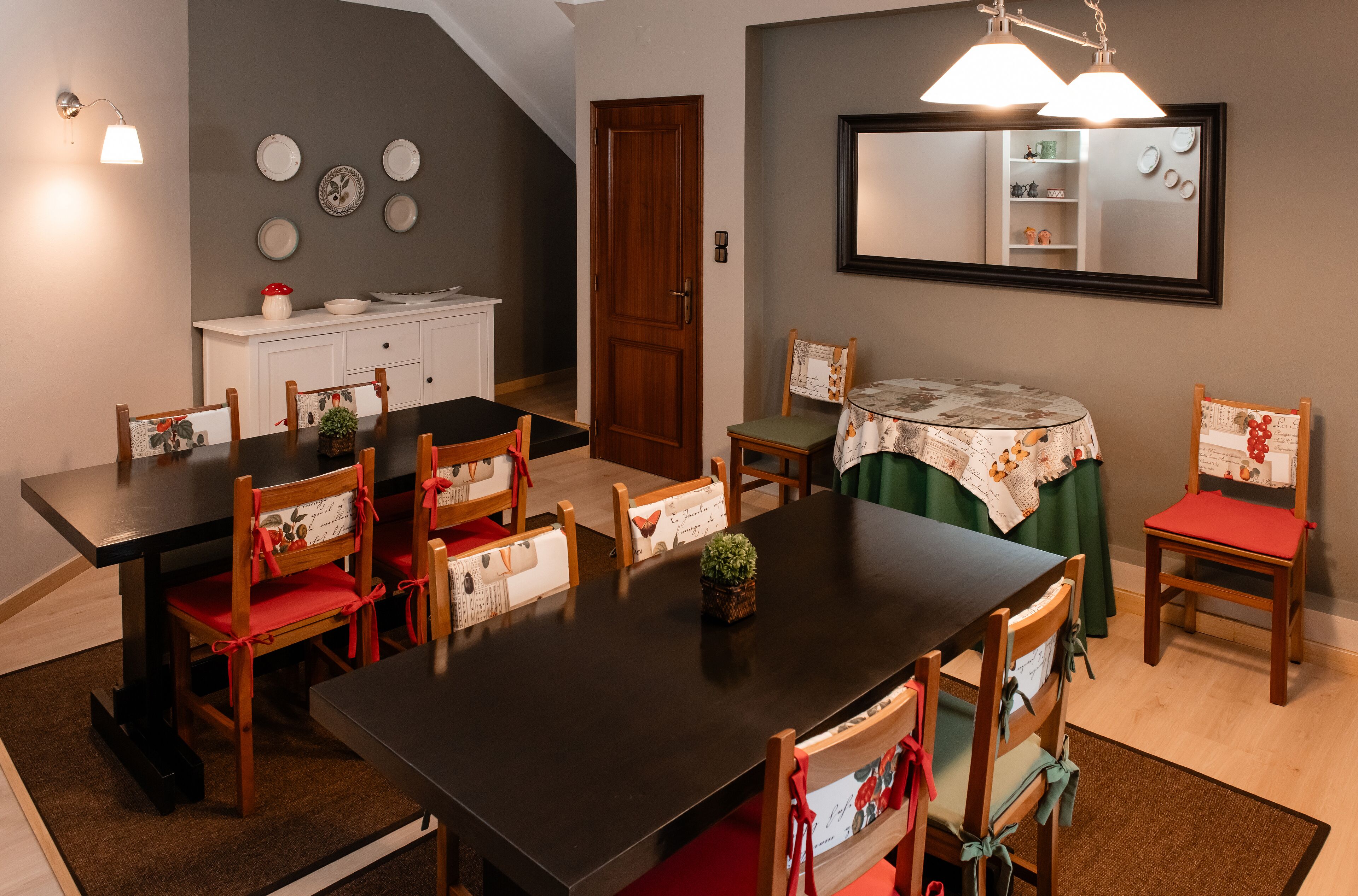 A dining area with a dark wooden table and chairs, a white cabinet, and a mirror on the wall.
