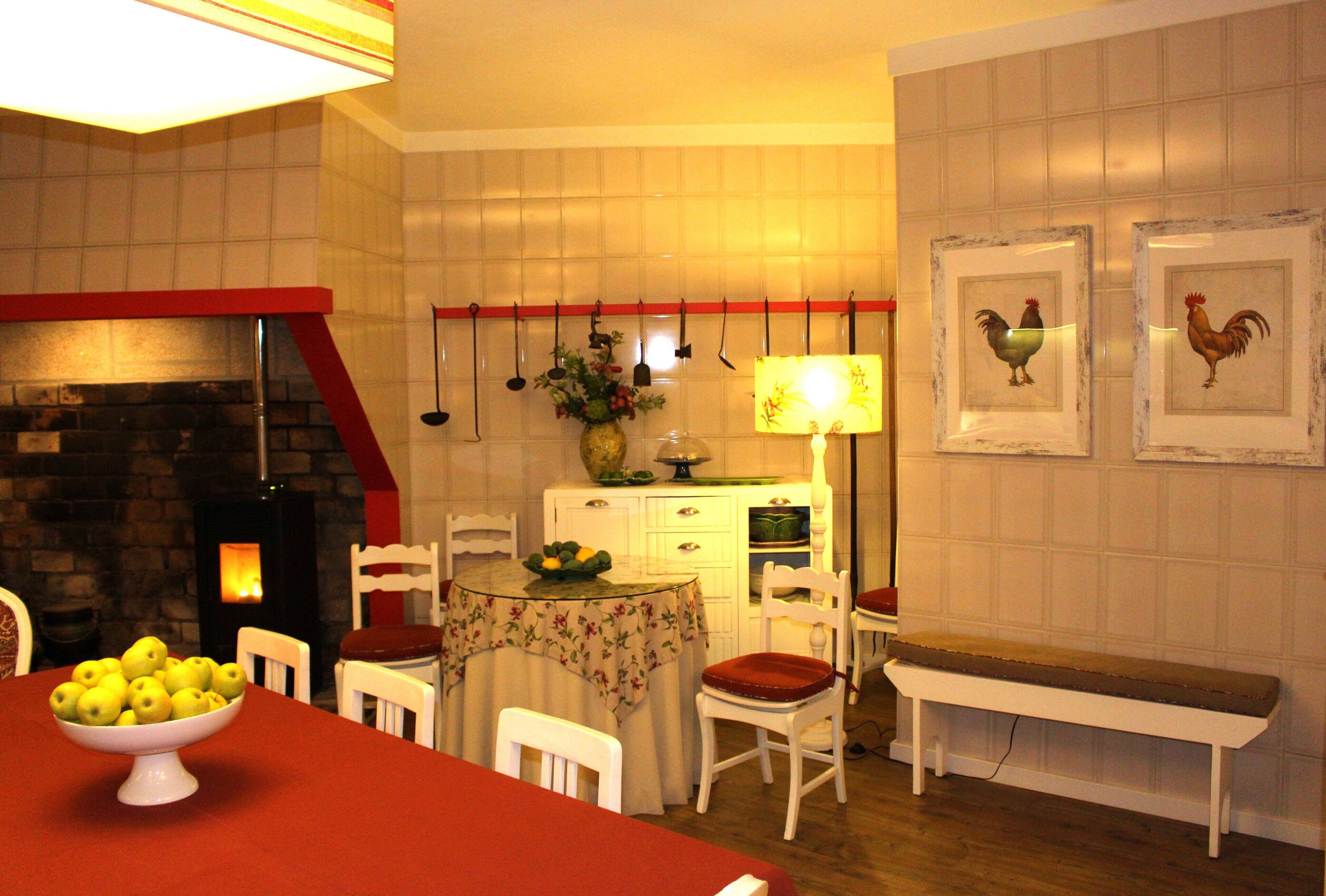 Un comedor con mesa dispuesta para cuatro, una banca, sillas, chimenea y decoraciones en la pared.