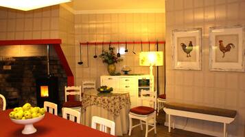 Un comedor con mesa dispuesta para cuatro, una banca, sillas, chimenea y decoraciones en la pared.