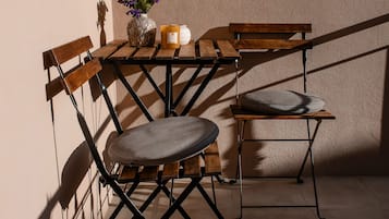 Une table en bois ornée d’un vase de fleurs et de bougies, deux chaises et un mur à la texture particulière.