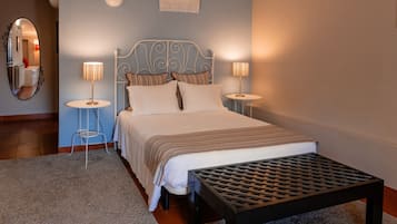 Ein ordentlich eingerichtetes Schlafzimmer mit einem Bett, zwei Nachttischlampen, einem kleinen Tisch und einem Spiegel.