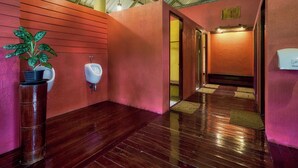 Ein modernes Badezimmer mit Holzböden, einem Blumentopf, einer Urinal und einem Duschbereich.
