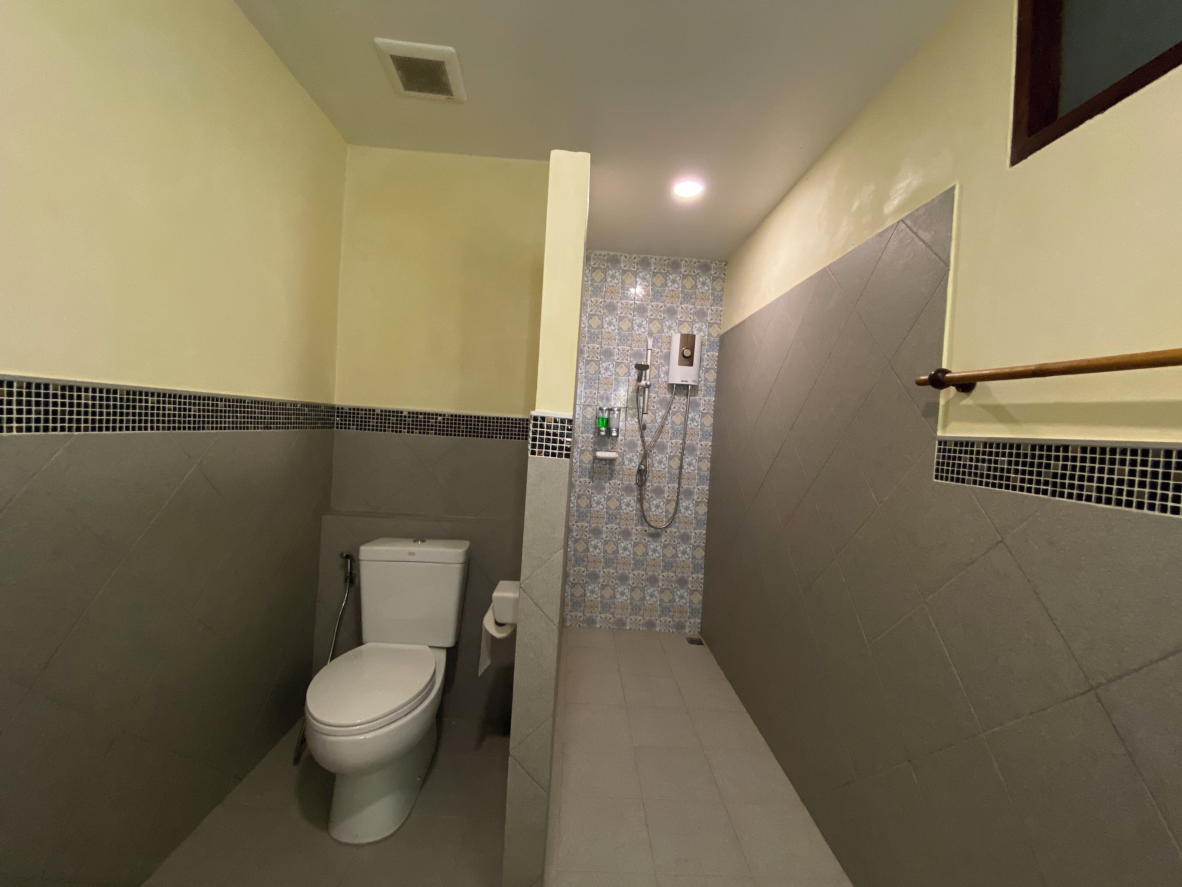A compact bathroom with a toilet, a shower, and a toilet paper holder.