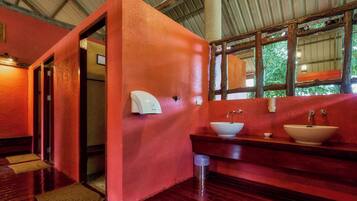 Un baño con pared roja, suelo de madera y un ventanal grande.