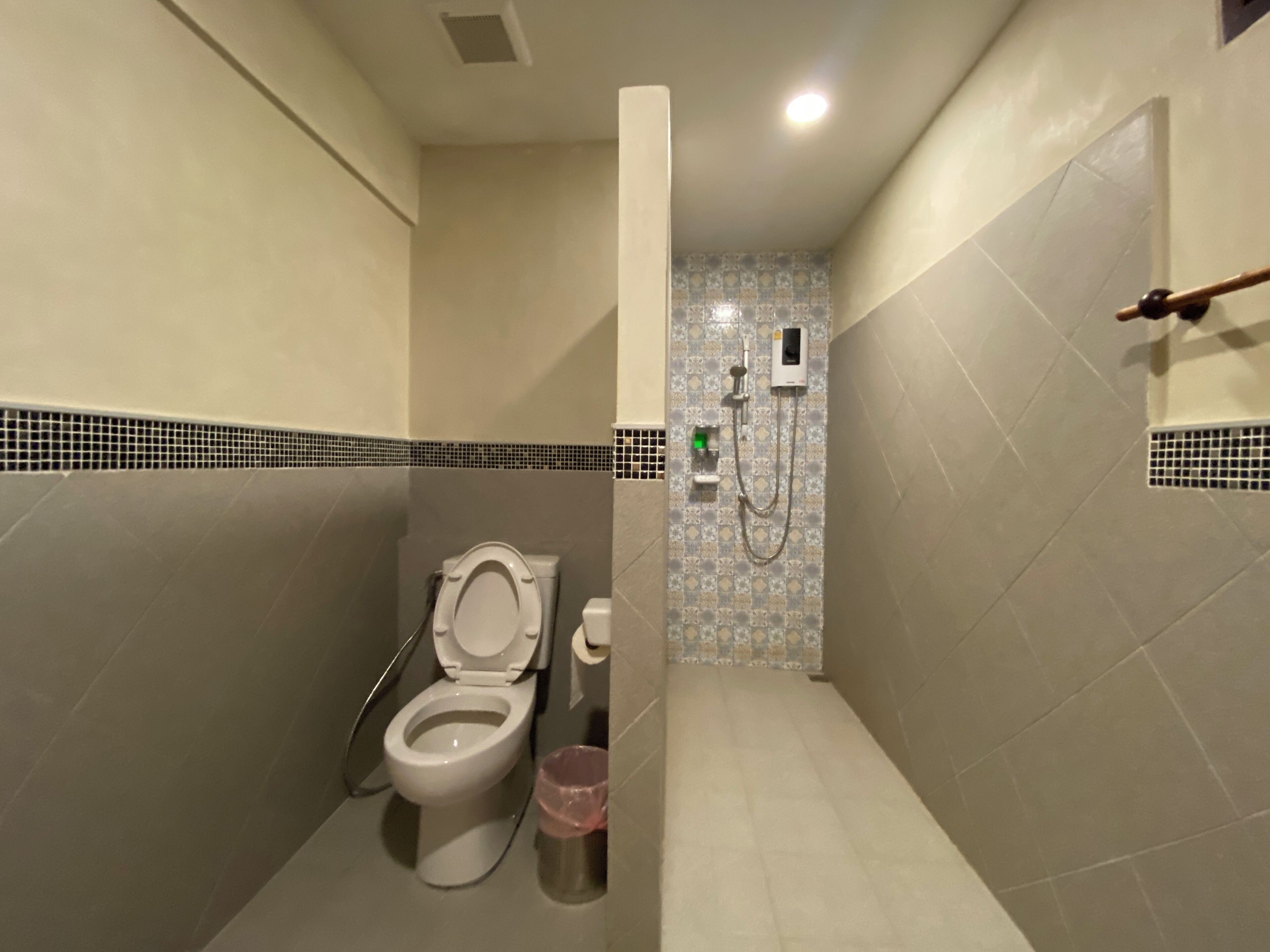 A compact bathroom with a toilet, a shower, and a hand dryer.
