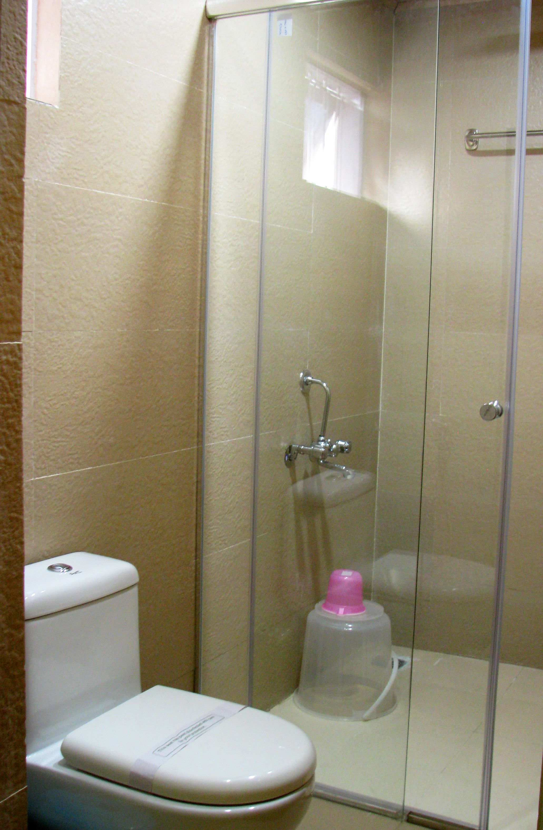 Un baño con inodoro, cabina de ducha y dispensador de jabón.