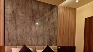 A hotel room with a marble-patterned wall, a wooden panel design, a bed with white bedding, and two swan-shaped towels. - Holiday Heaven Munnar (Devikolam)
