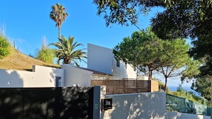 A modern building with a white facade, a wooden fence, and a view of the sea. - Place Of Moments Natur (Vila Franca do Campo)