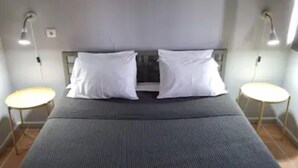 A neatly made bed with a grey bedspread, two white pillows, and two bedside tables with lamps. - Place Of Moments Natur (Vila Franca do Campo)