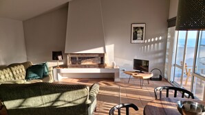 A living room with a fireplace, a sofa, a TV, and a dining area with a table and chairs. - Place Of Moments Natur (Vila Franca do Campo)