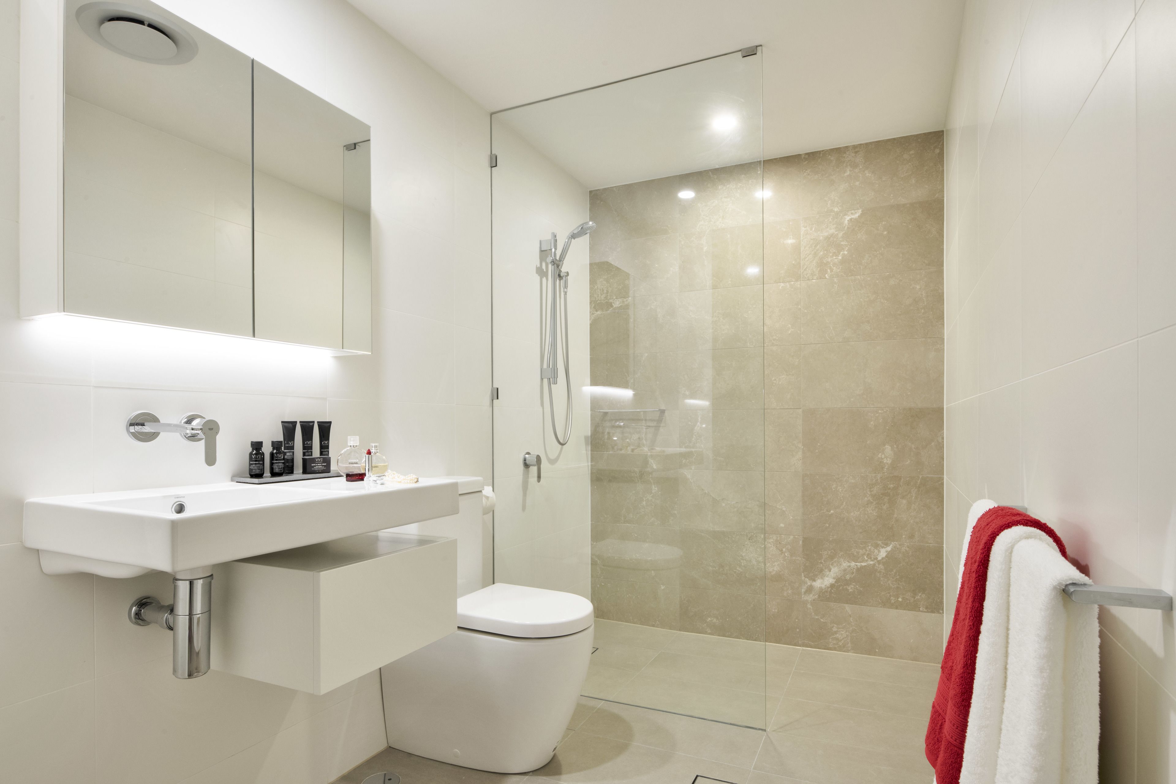 A modern bathroom with a white sink, toilet, and glass-enclosed shower.