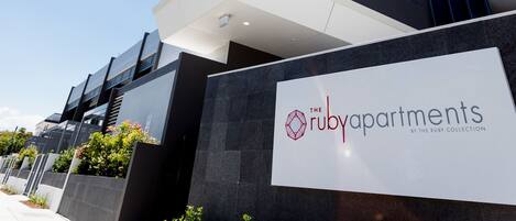 A modern high-rise building with a sign for 'The Ruby Apartments' by The Ruby Collection.