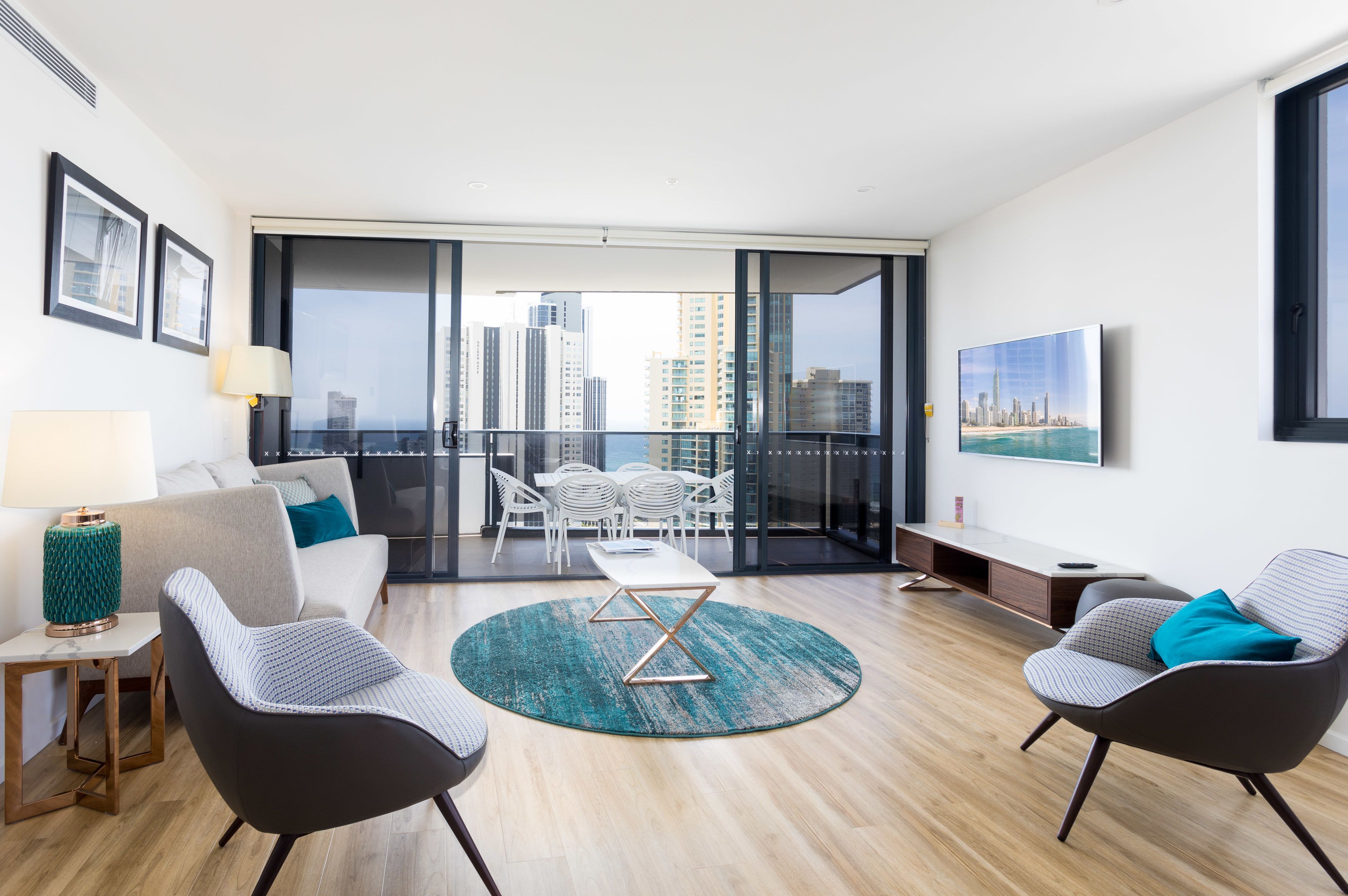 A modern living room with a sofa, two armchairs, a coffee table, and a view of the city skyline through large windows.