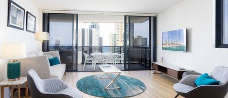 A modern living room with a sofa, two armchairs, a coffee table, and a view of the city skyline through large windows.