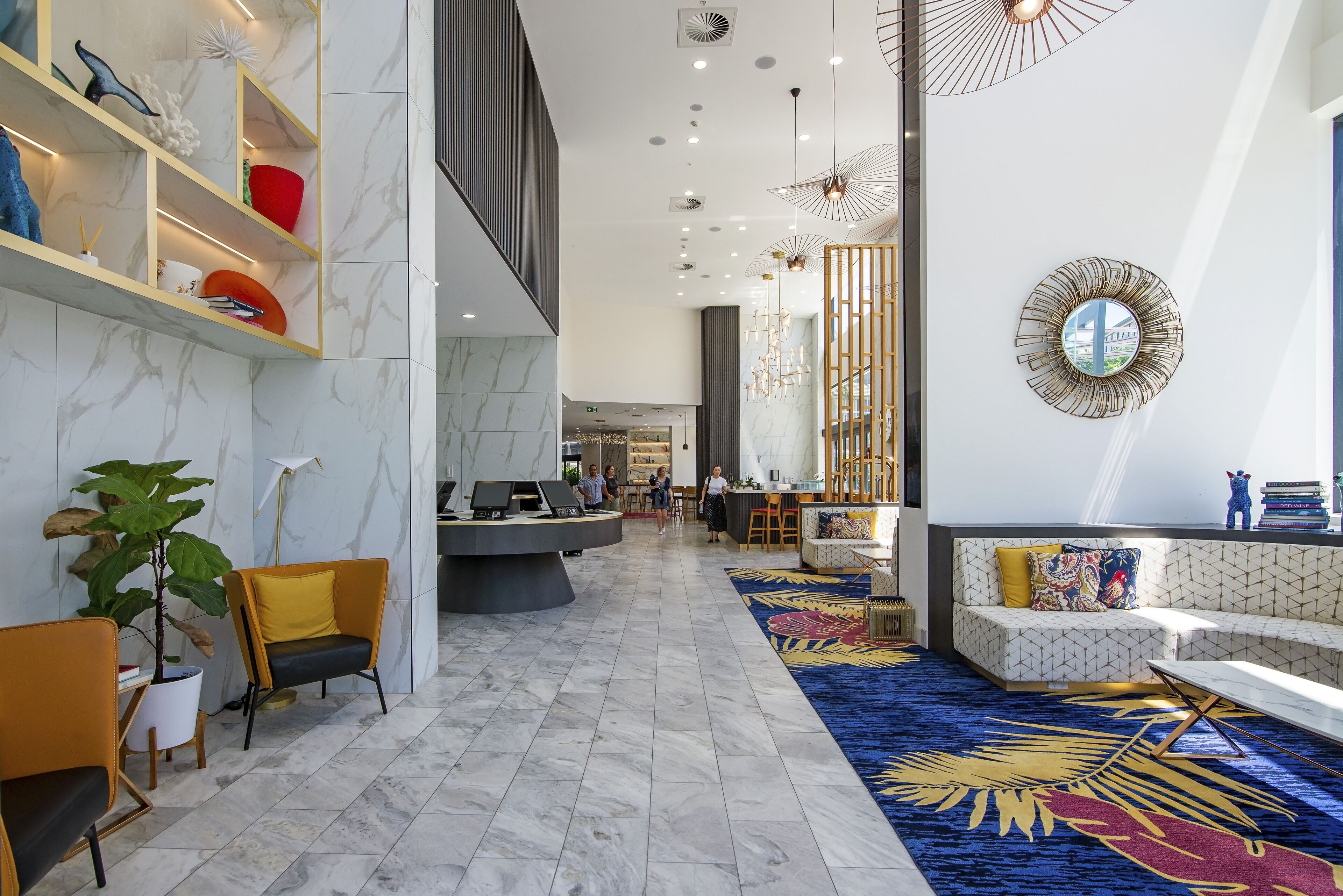 A modern lobby with marble flooring, a reception desk, seating areas, and decorative lighting.