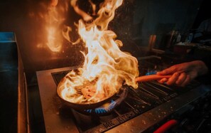 A person cooking on a portable stove with flames. - Rizmy Hotel (Cabuyao)