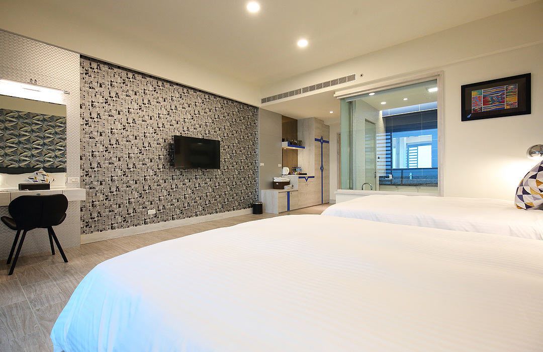 Una habitación de hotel moderna con dos camas, televisión, escritorio y baño con ventana grande.