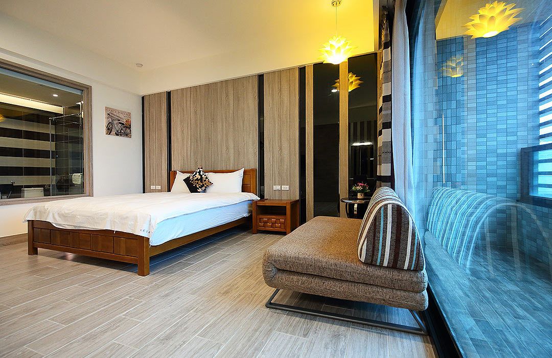 Une chambre à coucher comprenant un lit, un canapé, une table de chevet, un miroir et une fenêtre avec des stores.